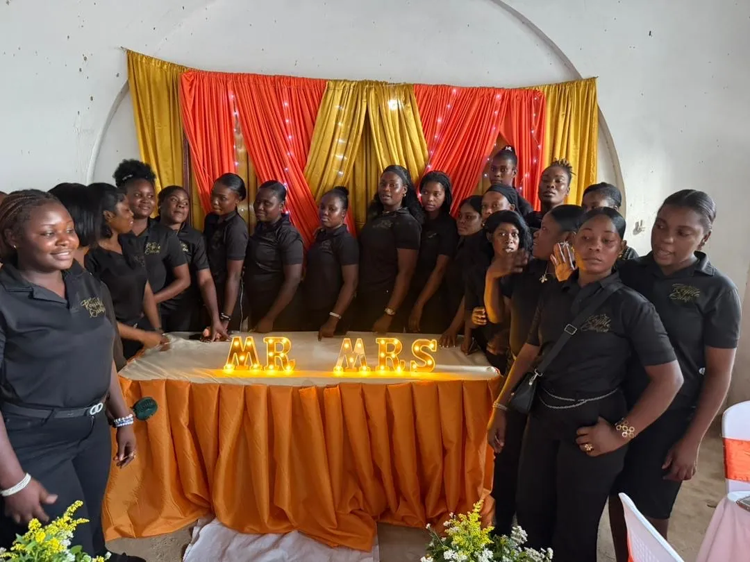 Groupe d’étudiantes de Royale Création en polos noirs devant des draperies rouges et dorées